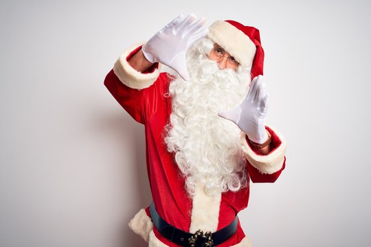 Middle age handsome man wearing Santa costume standing over isolated white background doing frame using hands palms and fingers, camera perspective