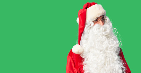 Middle age handsome man wearing Santa Claus costume and beard standing smiling looking to the side and staring away thinking.