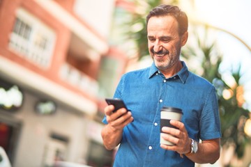 Middle age handsome businessman standing on the street using smartphone drinking take away coffee smiling