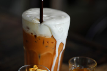 Iced milk tea with milk foam overflowing with aromatic syrup.