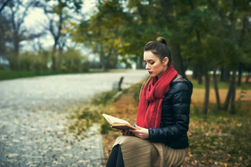 A young girl reading a book in the autumn Park .