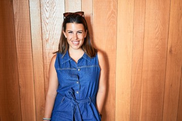 Fototapeta premium Young beautiful woman smiling happy and positive over wooden wall