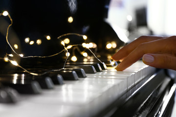 Woman playing piano with glowing garland, closeup