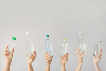 Female hands with bottles of water on grey background