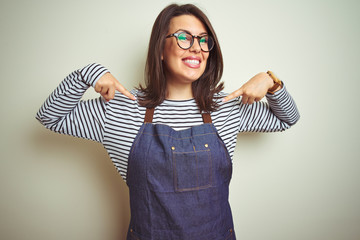 Young beautiful business woman wearing store uniform apron over isolated background looking...