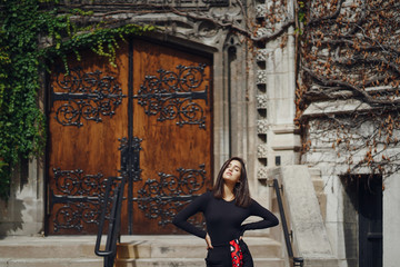stylish brunette standing next to the entance to a building at University of Chicago