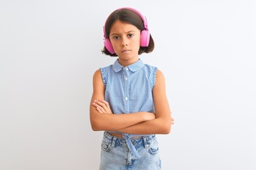 Beautiful child girl listening to music using headphones over isolated white background skeptic and nervous, disapproving expression on face with crossed arms. Negative person.