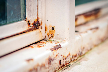 Close up of rust on an old white iron window in the corner of the frame with a blurred background