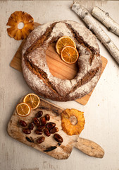 Fototapeta premium Round rye grain bread with dried fruits on wood cutting board
