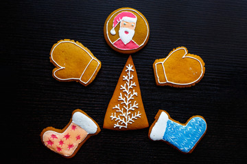 Handmade festive gingerbread cookies in the form of stars, snowflakes, people, socks, staff, mittens, Christmas trees, hearts for xmas and new year holiday on black wooden background