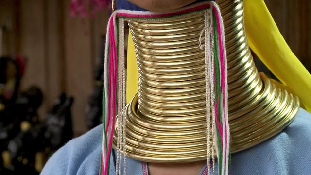 A daylight extreme closeup shot of layers of gold rings coiled around the neck of a native woman of Kayan (Padaung).