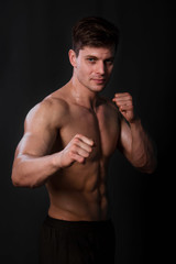 Fototapeta premium Muscular bodybuilder posing with a naked torso against a black background. Sexy man.