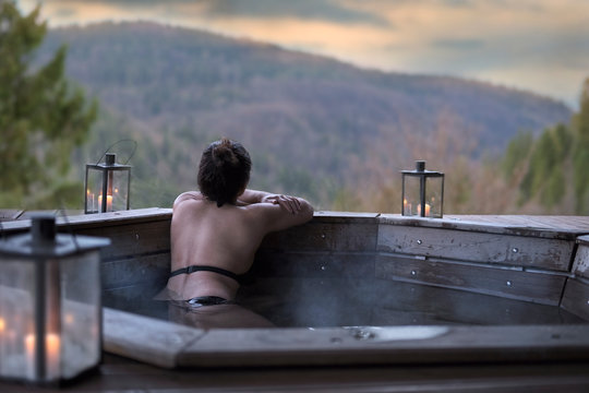 The young woman in an open-air bath with a view of the mountains.