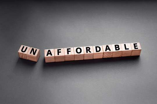 unaffordable to un affordable- words from wooden blocks with letters, too expensive concept, top view gray background