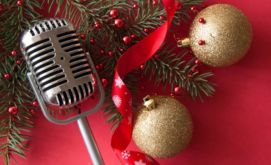 Microphone and fir branches against red lights, space for text.