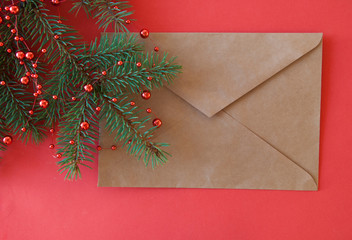Fototapeta na wymiar Christmas and New Year background with fir branches and brown envelope on red paper background.