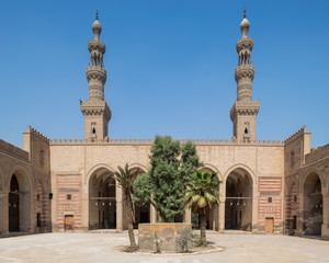 Fototapeta na wymiar Courtyard of Mamluk era al Nasir Faraj ibn Barquq public historical mosque with minarets of the mosque, Al Darb Al Ahmar district, Cairo, Egypt