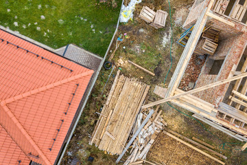 Top down aerial view of two private houses, one under construction with wooden roofing frame and...