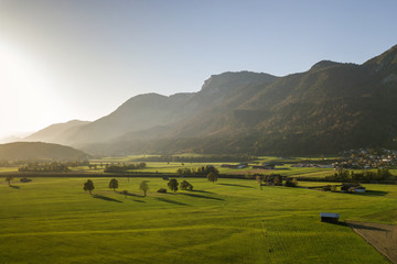 Aerial view of green meadows with villages and forest in austrian Alps mountains.