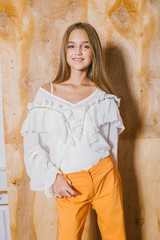 Attractive young girl with blond hair and evening make-up in retro flared pants and a chiffon boho...