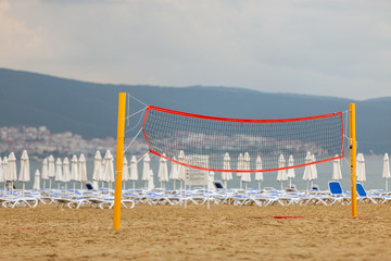 Empty volleyball net on a sandy beach on the sea shore in summer.