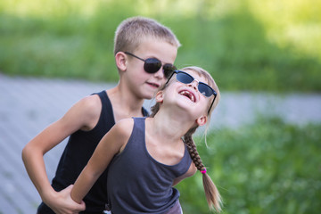 Two children in black sunglasses having fun time outdoors in summer.