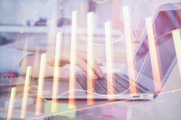 Double exposure of stock market graph with man working on laptop on background. Concept of financial analysis.