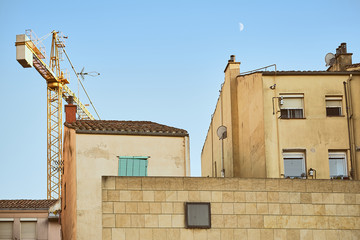 Fototapeta na wymiar moon in the blue sky with stone old buildings and crane