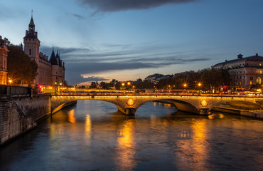 Fototapeta na wymiar Stone bridge Pont au Change in Paris at the dusk. On the left are towers of Conciergerie, on right northern bank of river Seine