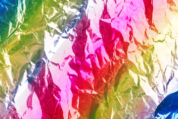 Crumpled rainbow wrapping paper with shiny effect. Close up.