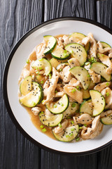 Fried chicken fillet with zucchini in spicy sauce close-up on a plate. Vertical top view