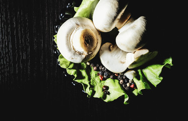 fresh champignons on an old surface with lettuce on a black background