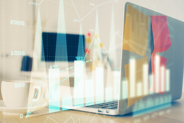 Stock market graph on background with desk and personal computer. Double exposure. Concept of financial analysis.