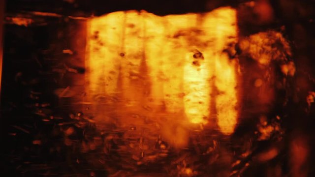 Background of bubbles of boiling water in a transparent bowl where a fire burns in the background