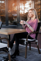 Beautiful woman drinks cappiccino at sunset outdoors.