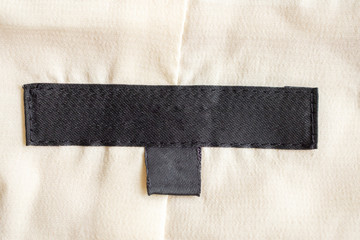 Blank black laundry care clothing label on fabric texture