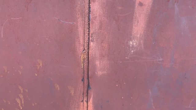 The camera shows welded hinges on a rusty metal door. Close-up