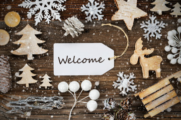 One White Label With English Text Welcome. Frame Of Christmas Decoration Like Tree, Sled, Star And Fir Cone. Wooden Background With Snowflakes