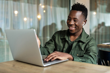 Handsome african american man using computer and smiling. young businessman recording video for online webinar using laptop