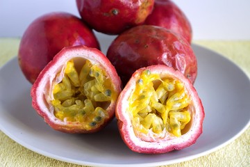 Some passion fruit on a plate. One of the fruit is cut in half, showing its interior