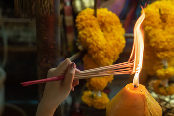 Religious Asian buddhist woman pray and light up joss stick incense. Female buddhist disciple...