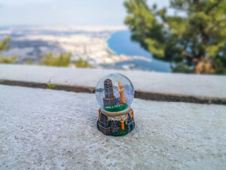 Glass snow ball with Antalya against the backdrop of a blurred cityscape of Antalya. The concept of winter holidays in a tropical warm resort, a trip to Turkey