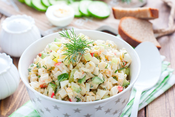 Salad with crab sticks, fresh cucumbers and rice in a white bowl, horizontal