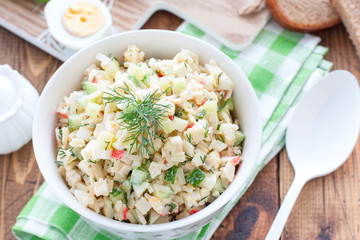 Salad with crab sticks, fresh cucumbers and rice in a white bowl, horizontal