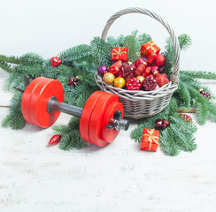Christmas or New Year on a white background. Composition with dumbbells, gift, red glass balls, fir tree branches for healthy lifestyle and sport