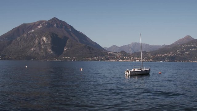 boat floats moored in the middle of the lake among the mountains, Wide, Slow Motion, Varenna, Italy.