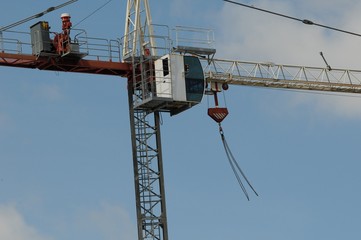 A Working Construction crane high in the sky on a building site with strong wind blowing the empty...