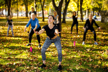 Naklejka na ściany i meble large group of people doing outdoor workout on green grass in park
