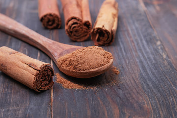 Ceylon cinnamon sticks and powder in the spoon on a wooden background