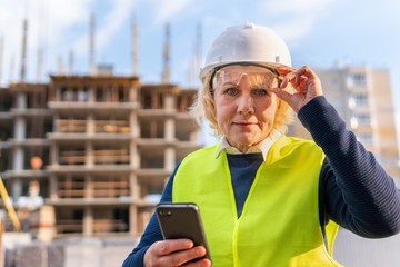 A female builder worker at a construction site works and controls the process.